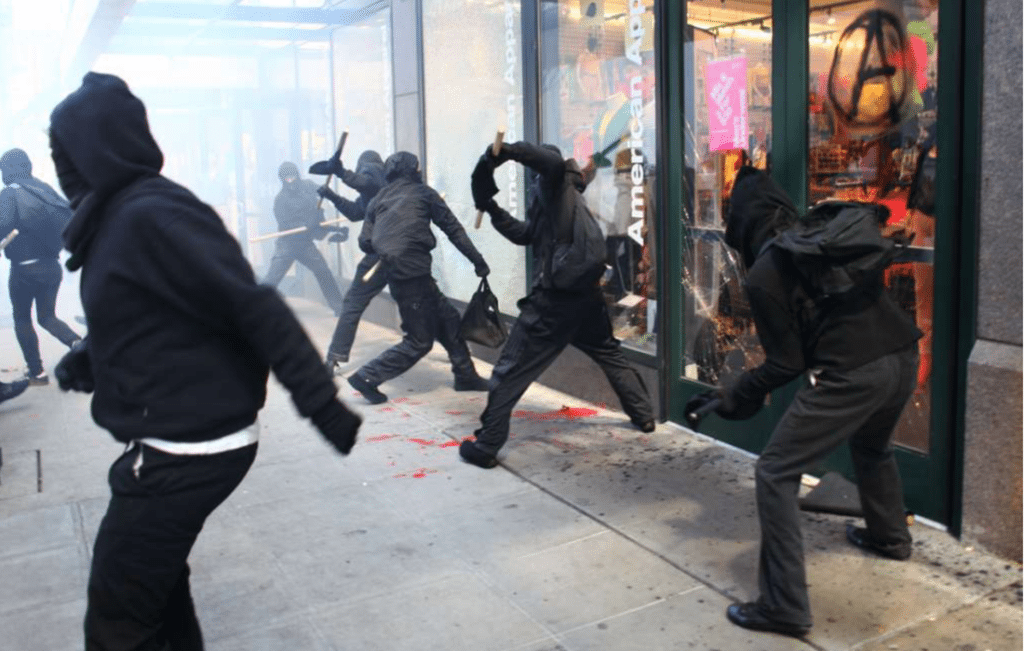 rioters in black breaking glass