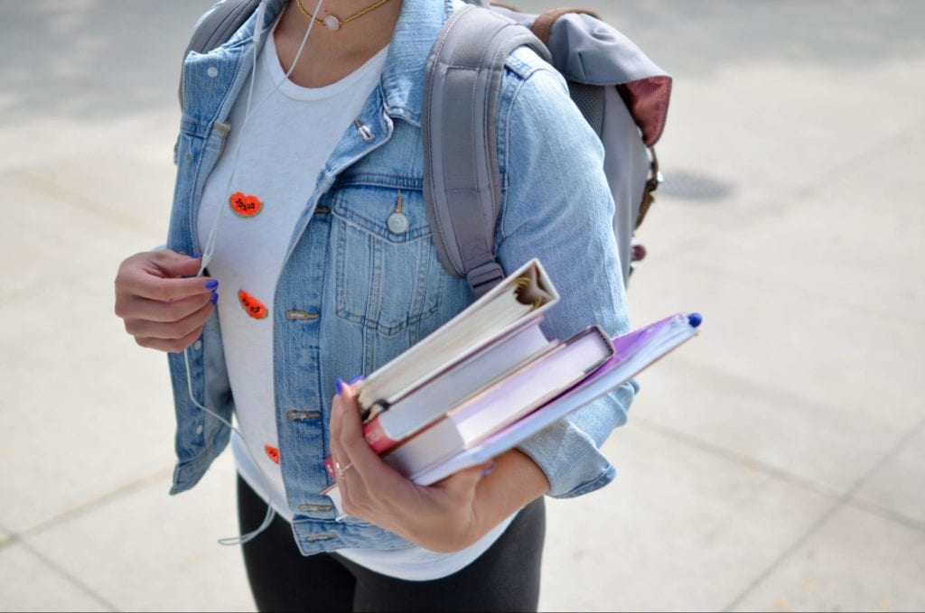 female student holding books and with earphones