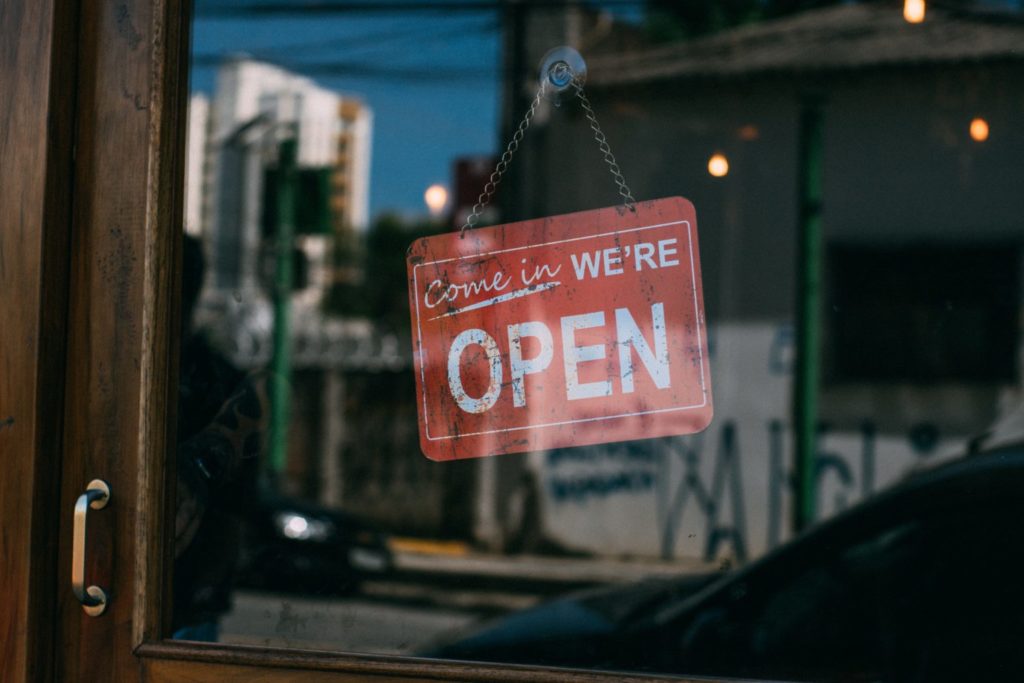 "come in we're open" red sign on glass door