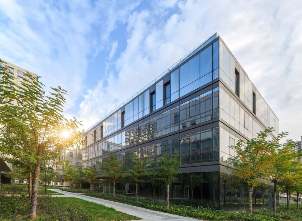 corner of big glass building with trees surrounding