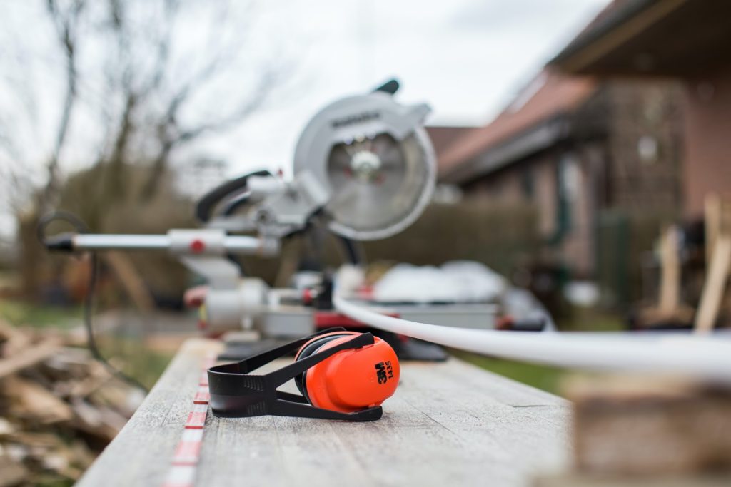 ear muff headphones in board with saw behind it