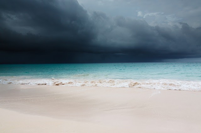 sand meets ocean with dark clouds hanging over
