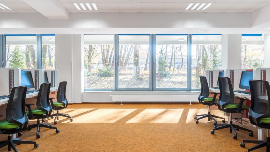 office spacec filled with chairs and computers with large window walls