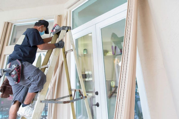 man on ladder against window doors