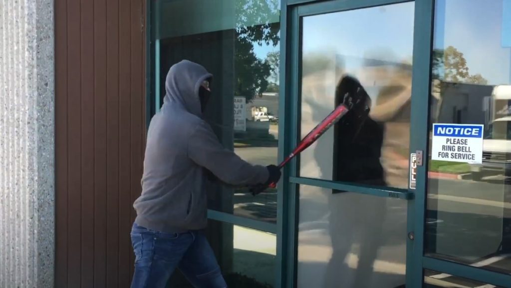 intruder trying to break glass with baseball bat