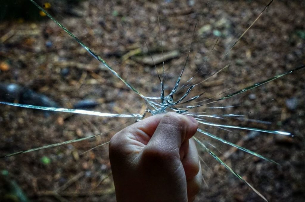 hand holding a piece of shattered glass