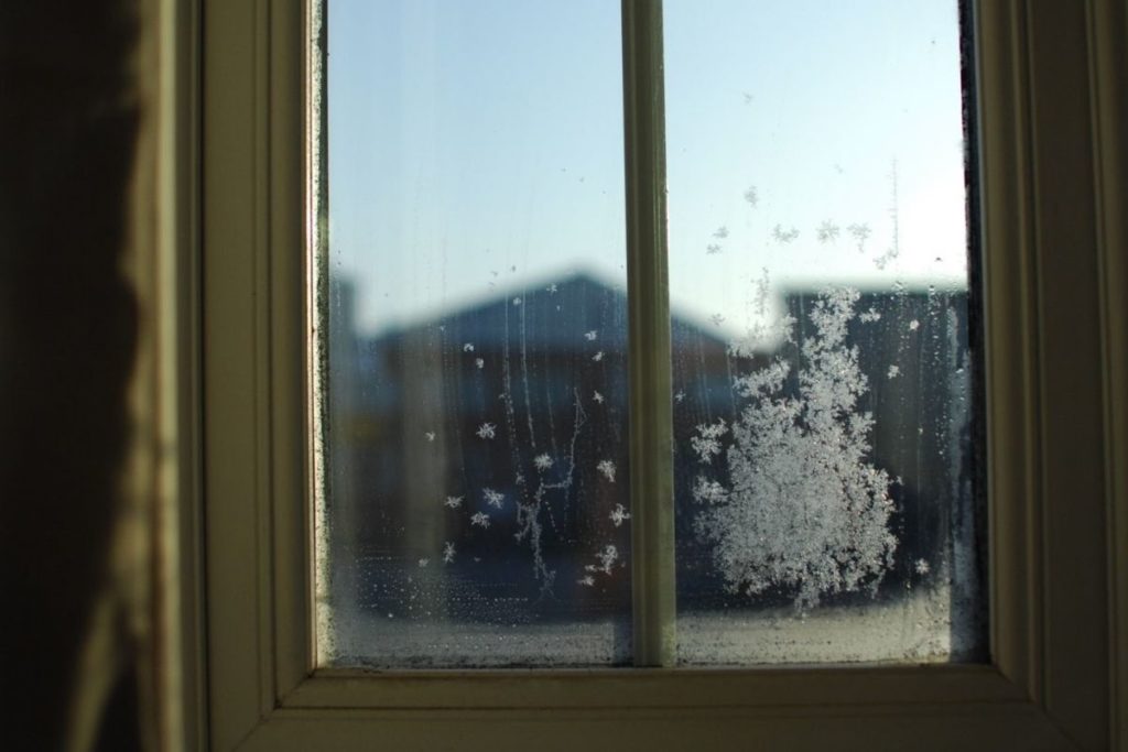 a cluster of frozen snowflakes on window looking outside