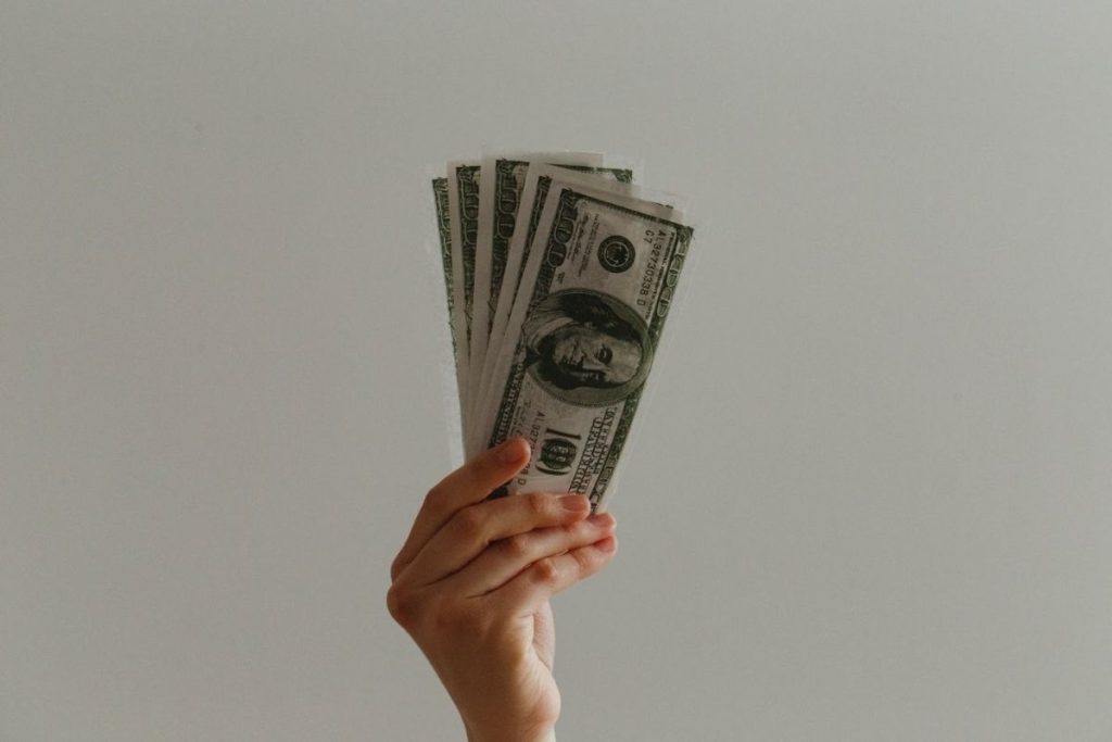 hand holding five 100 dollar bills up
