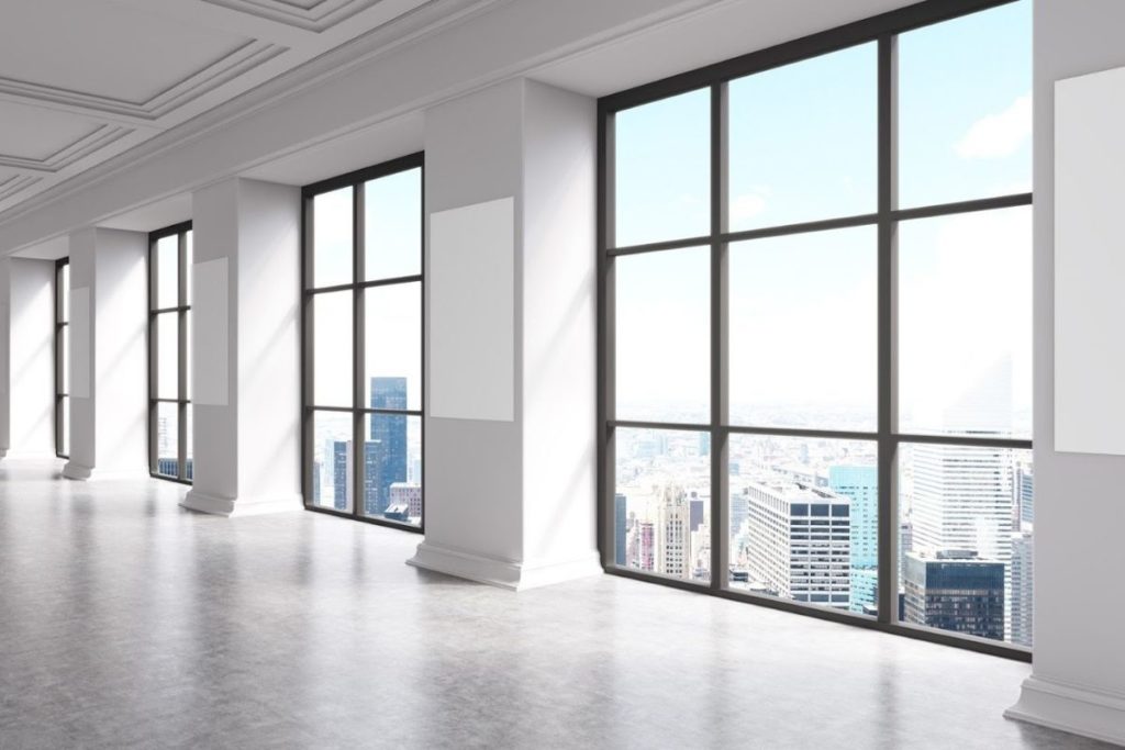 rows of windows inside industrial building looking out at skyscrapers